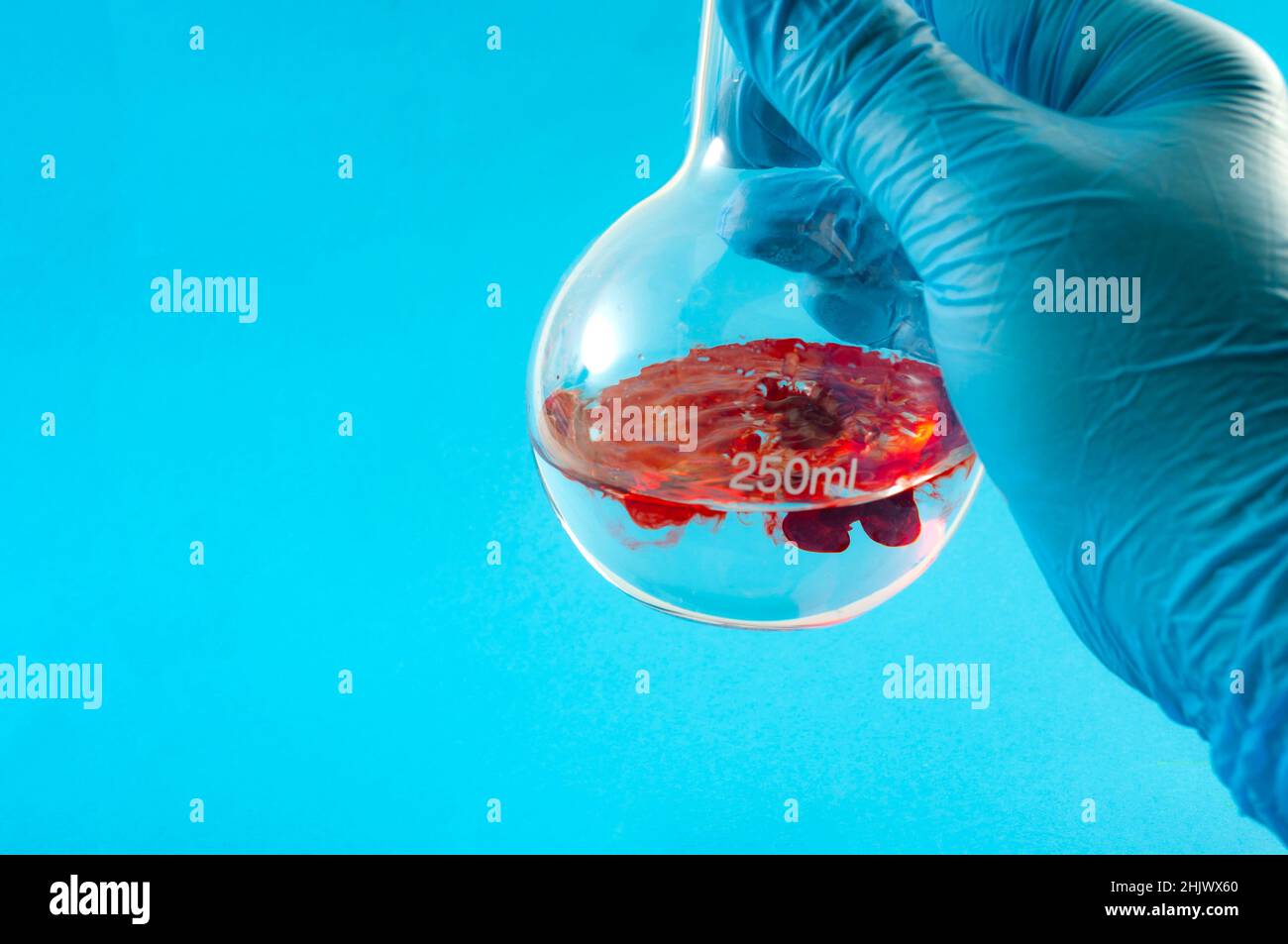 Esperimento scientifico, reazione chimica e concetto di chimica sperimentale con mano di scienziato in guanti di gomma blu, versando un liquido rosso in un fl Foto Stock