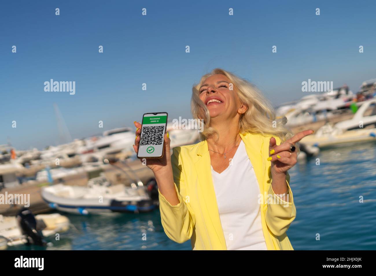 Donna felice con smartphone e passaporto sanitario digitale Foto Stock