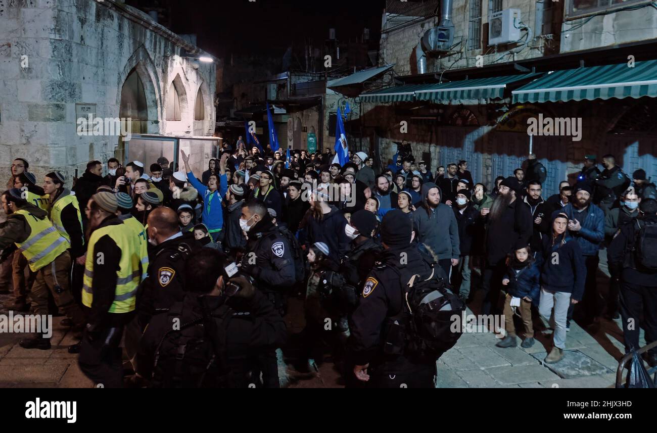 I membri delle forze di sicurezza israeliane stanno in guardia mentre gli ebrei religiosi camminano attraverso il quartiere musulmano durante la celebrazione 'Shaarim' (Circling of the Gates) intorno alle porte del Monte del Tempio il 31 gennaio 2022 a Gerusalemme, Israele. L'evento si svolge ogni primo giorno del nuovo mese nel calendario ebraico. Durante la cerimonia, gli adoratori circondano il Monte del Tempio, cantando e ballando mentre passano ciascuna delle sue porte. Foto Stock