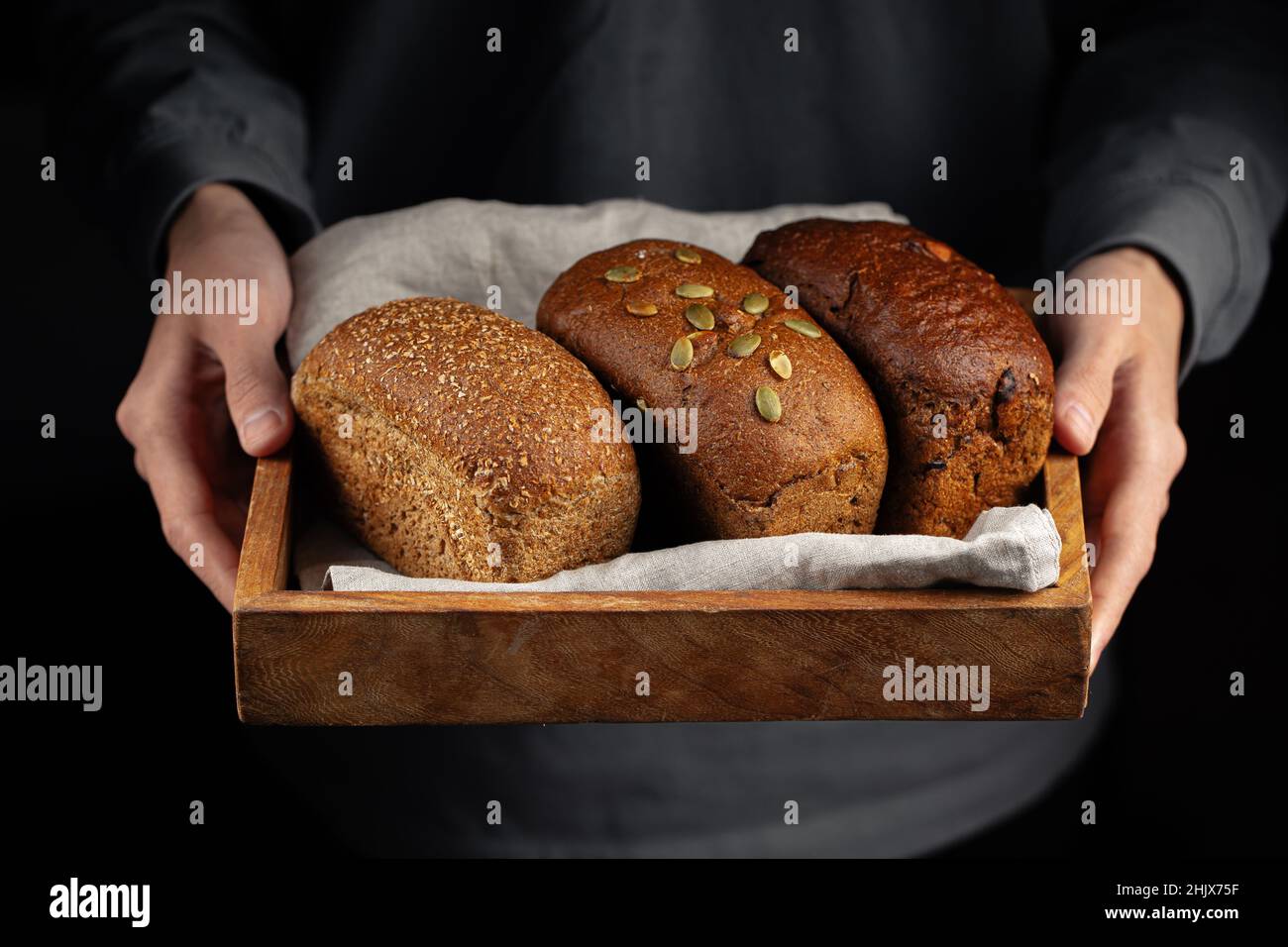 Uomo che tiene vassoio di legno di pane assortito Foto Stock