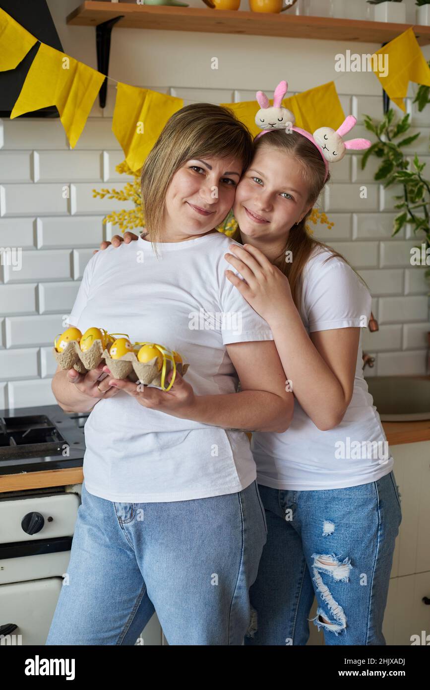 Mamma e figlia in posa con uova di Pasqua in cucina. Foto Stock