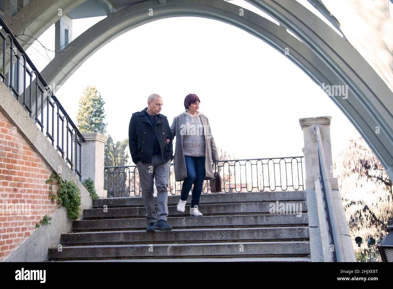 due persone anziane che tengono le mani calando le scale in città Foto Stock