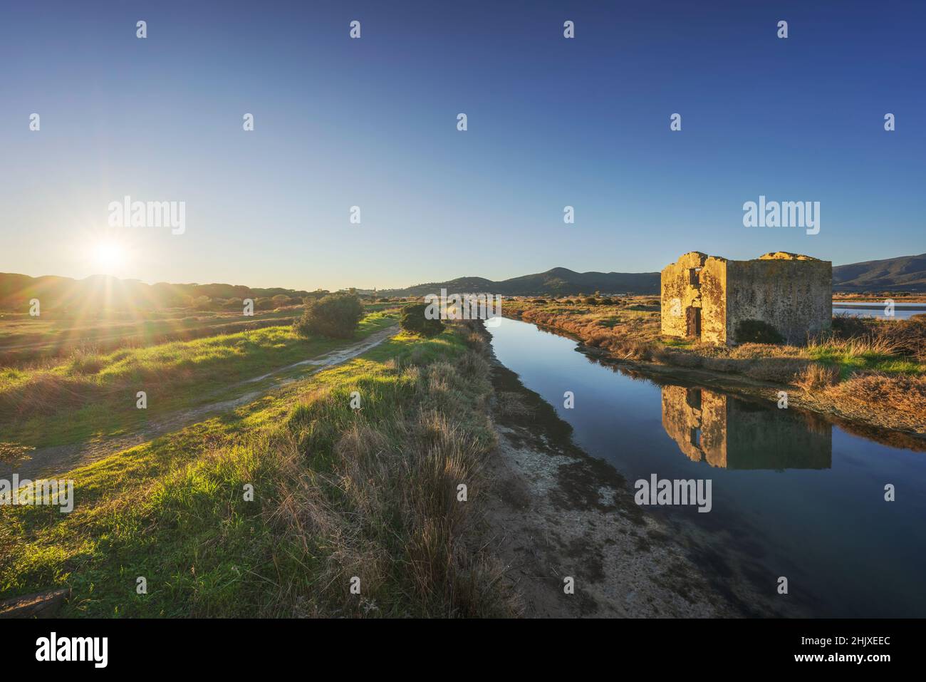 Castiglione della Pescaia al tramonto, canale d'acqua Diaccia Botrona e una rovina di una casa. Riserva naturale di uccelli. Toscana, Italia, Europa. Foto Stock