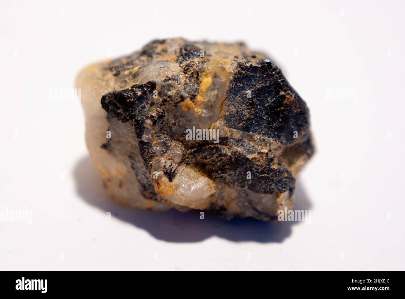 Piccola pietra di quarzo con biotite nera su sfondo bianco Foto Stock