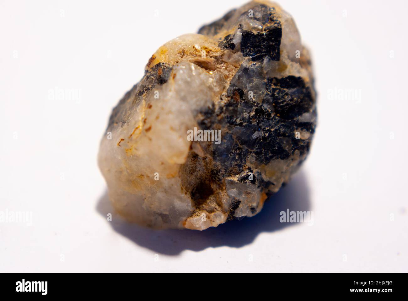 Piccola pietra di quarzo con biotite nera su sfondo bianco Foto Stock