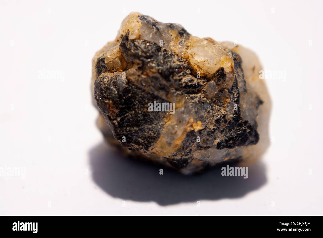 Piccola pietra di quarzo con biotite nera su sfondo bianco Foto Stock