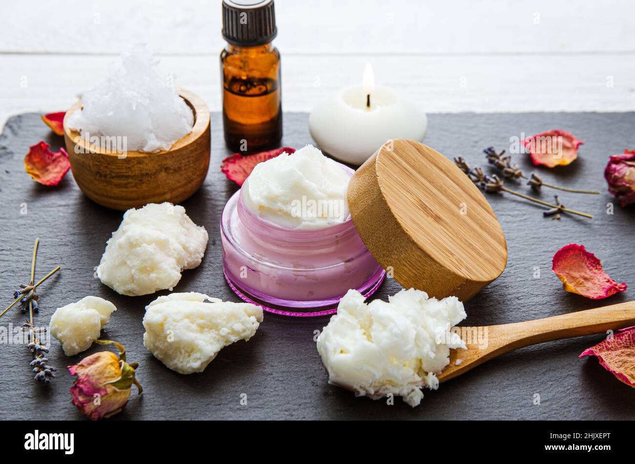 Fare bodywhip anche noto come burro corpo, crema idratante per la cura della pelle. Ingredienti su sfondo legno: Burro di karité, olio di cocco solido, oli essenziali. Foto Stock