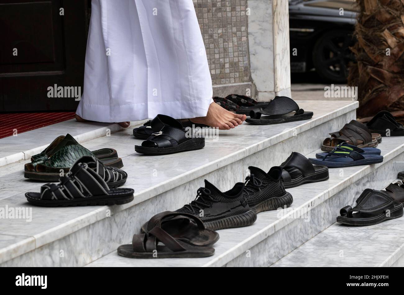 Frammento di foto, solo le gambe dell'uomo arabo che vanno dalla moschea dopo la messa. Gamba e molte scarpe fuori sulle scale. Scarpe di preghiera vicino moschea, islam r Foto Stock