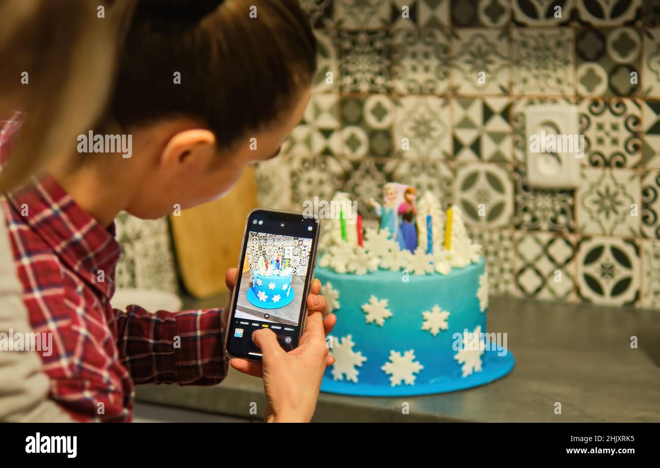 Femmina scatta foto per smartphone di dolce torta blu per i social media Foto Stock