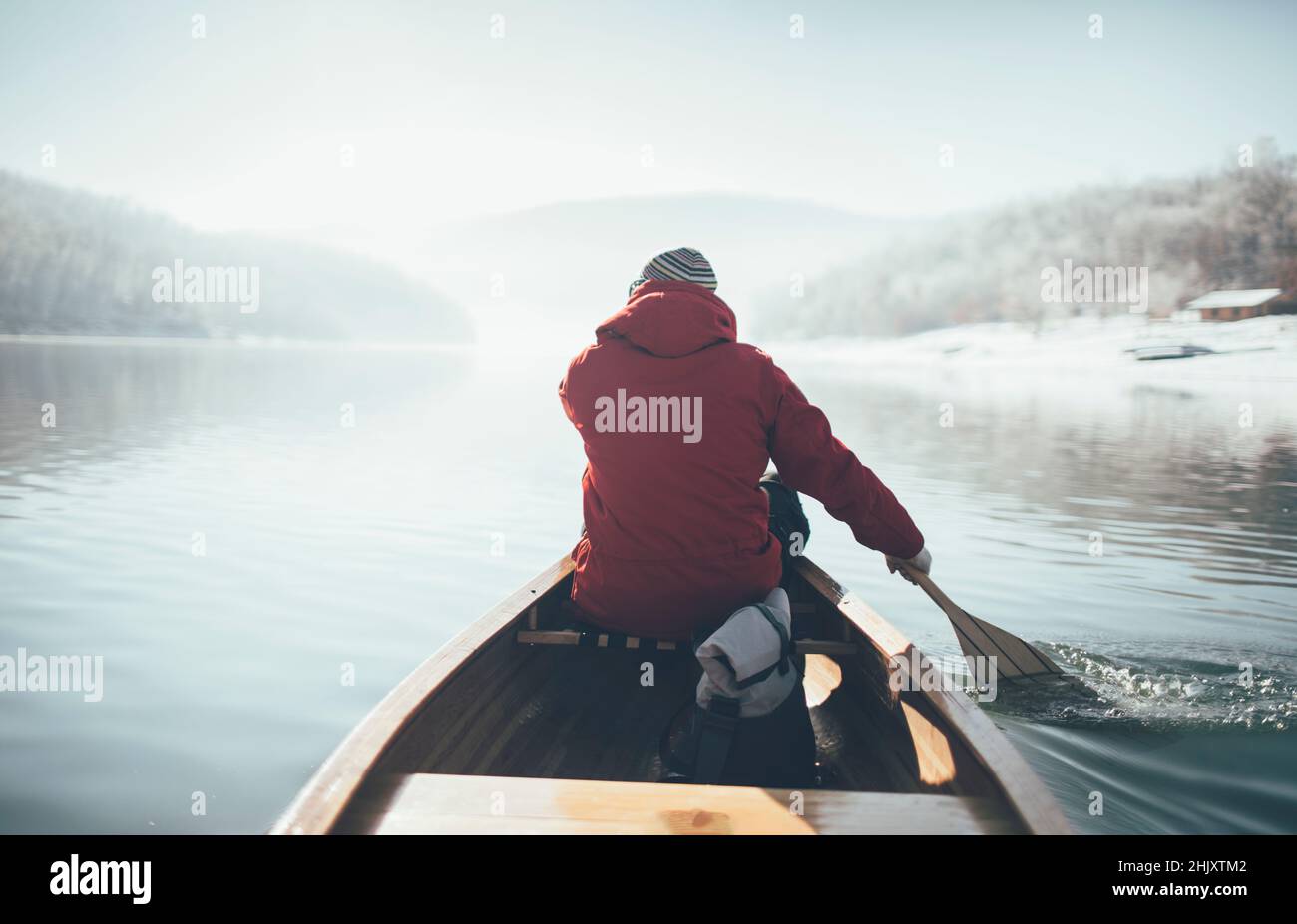 Vista posteriore della canoa uomo pagaiante nella giornata di sole d'inverno Foto Stock