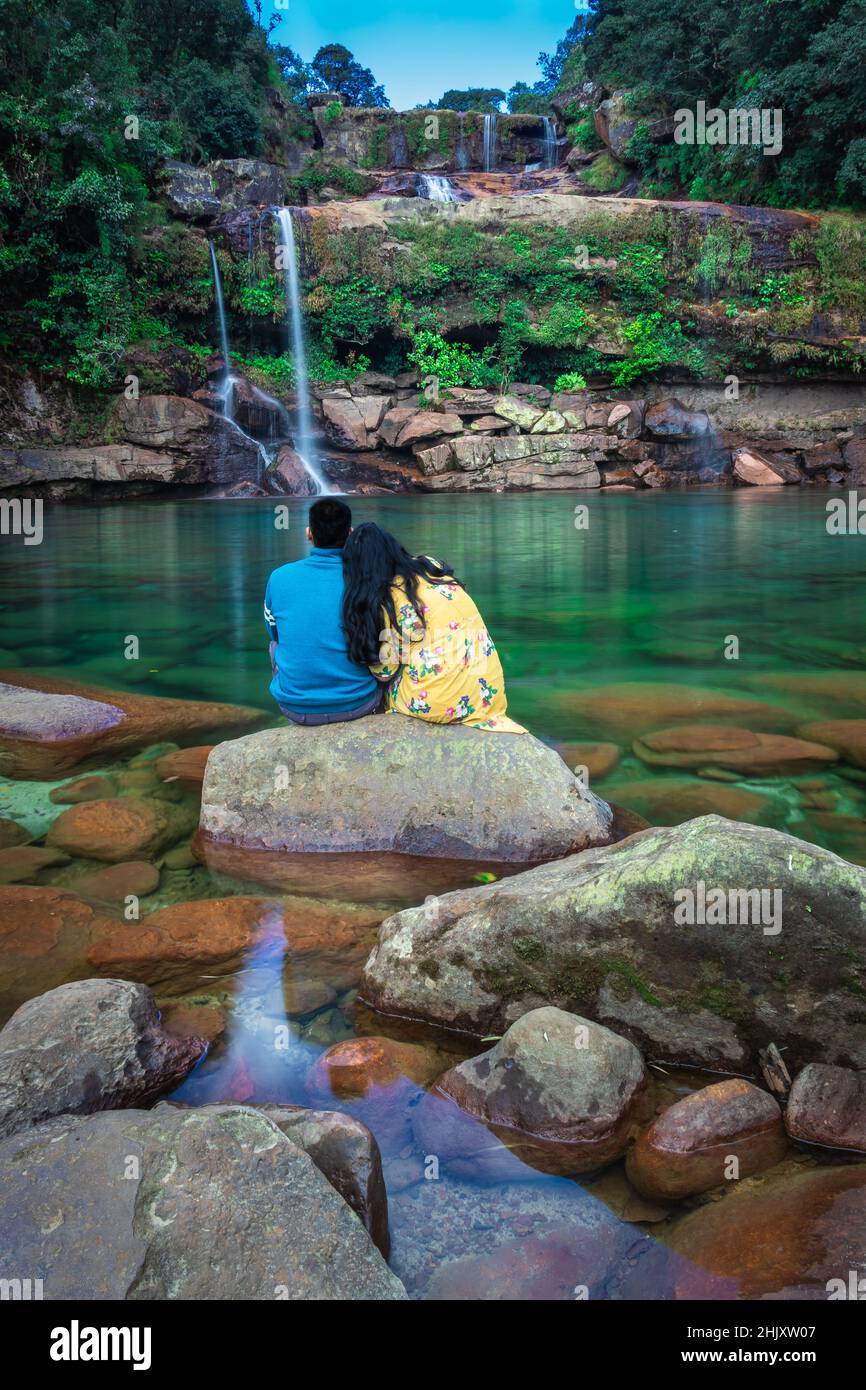 giovane coppia isolata seduta su roccia con sfondo incontaminato cascata al mattino in immagini foreste è preso a lyngksiar cascate cherrapunjee meghalay Foto Stock