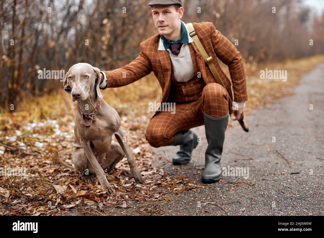 caucasico bel cacciatore uomo con cane da caccia grigio in foresta. Uomo seduto e cane a caccia all'aperto, persone e animali rapporto concetto, fr Foto Stock