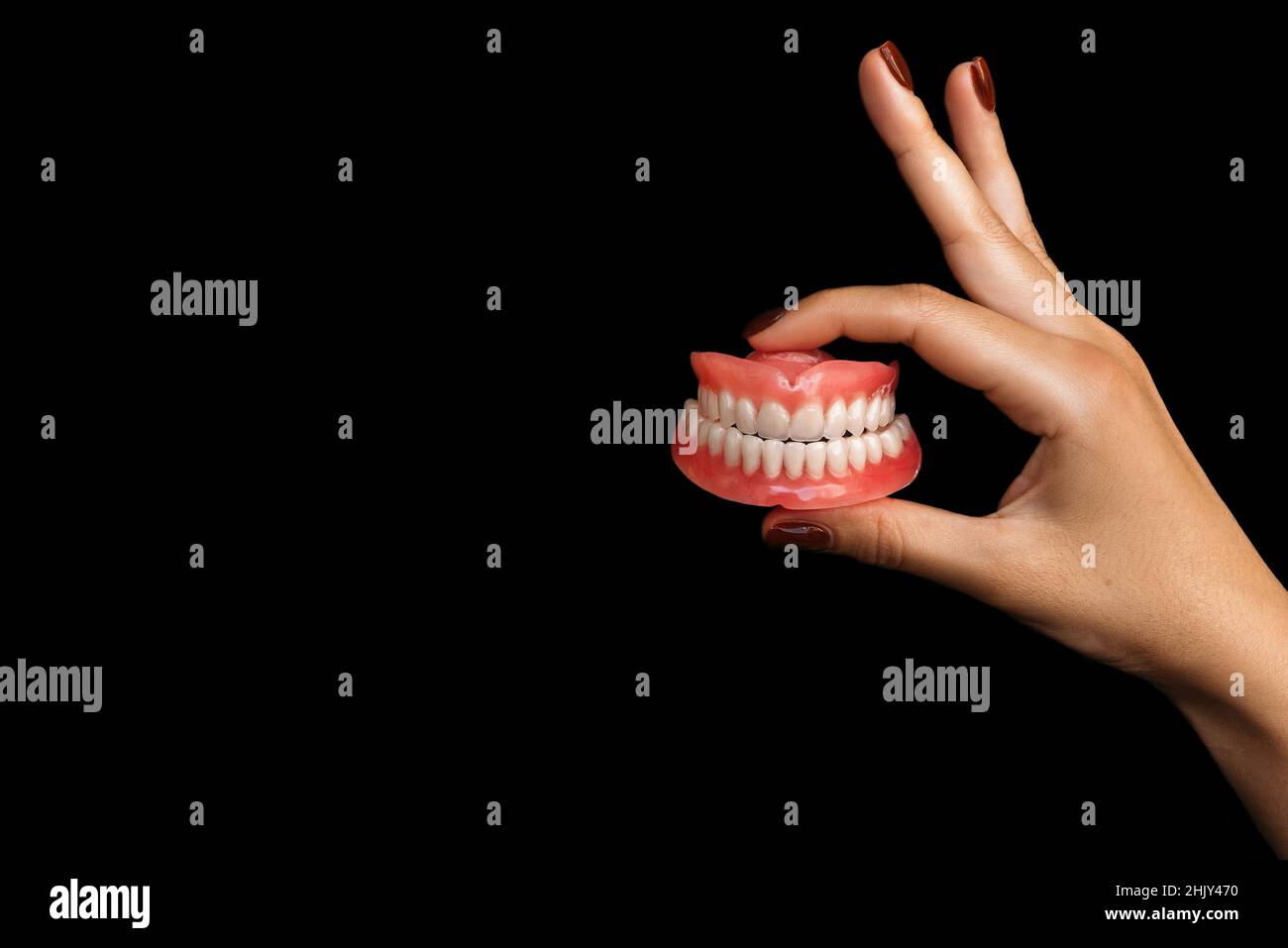 Il dentista tiene le dentarie nelle sue mani. Protesi dentaria nelle mani del medico primo piano. Vista frontale della dentiera completa. Dentini protesici Foto Stock