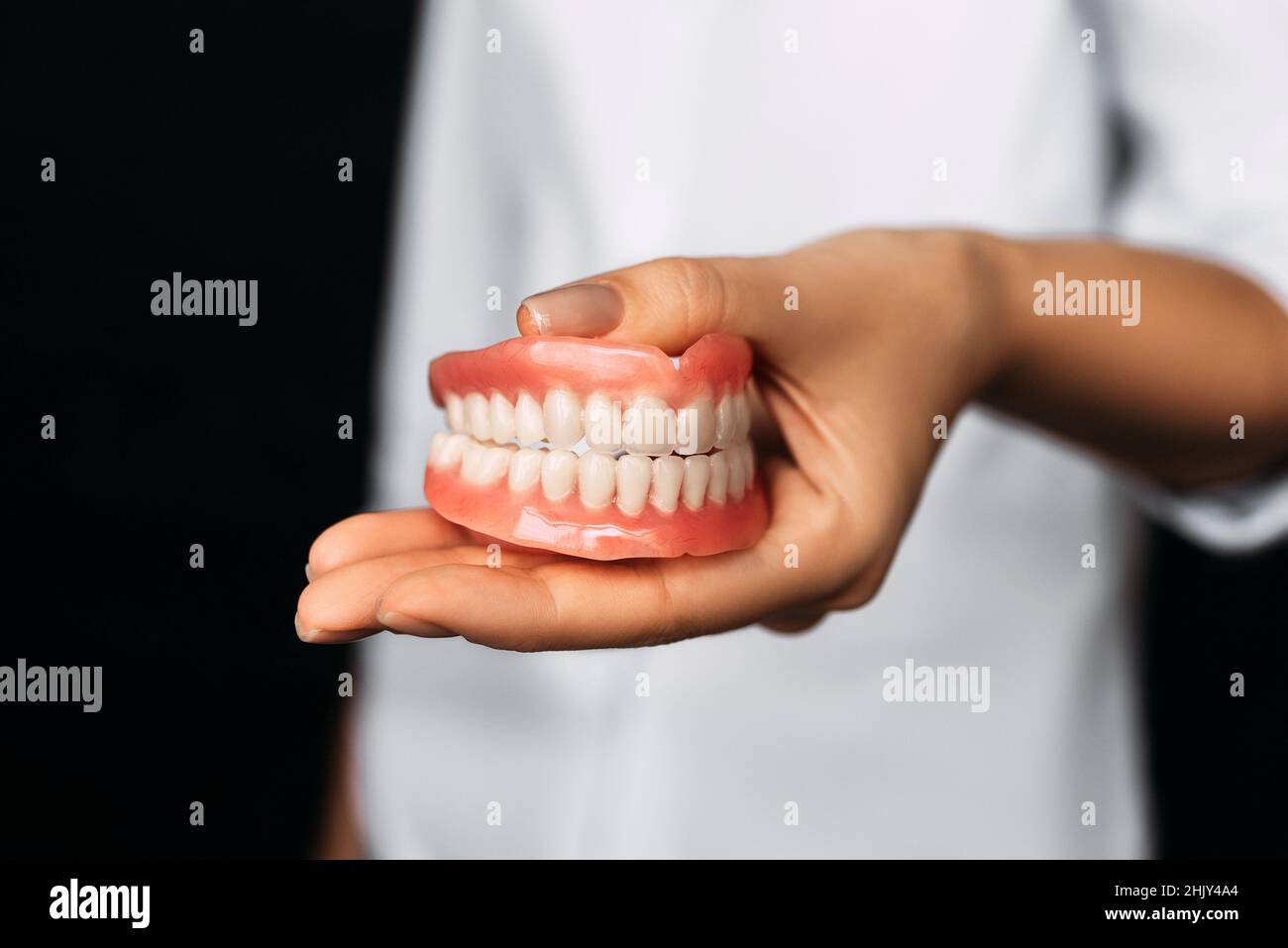 Il dentista tiene le dentarie nelle sue mani. Protesi dentaria nelle mani del medico primo piano. Vista frontale della dentiera completa. Odontoiatria concetto Foto Stock