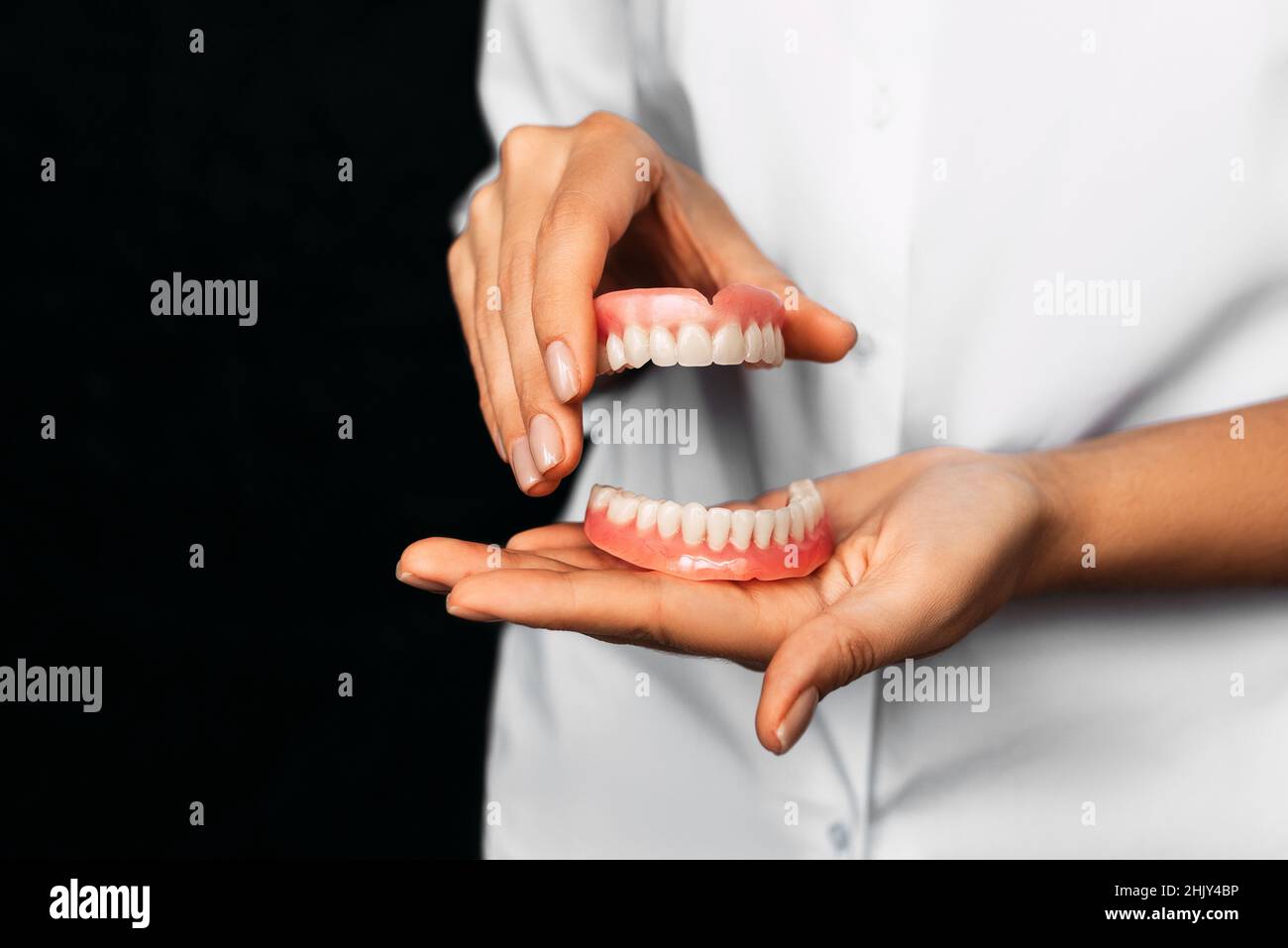 Il dentista tiene le dentarie nelle sue mani. Protesi dentaria nelle mani del medico primo piano. Vista frontale della dentiera completa. Odontoiatria concetto Foto Stock