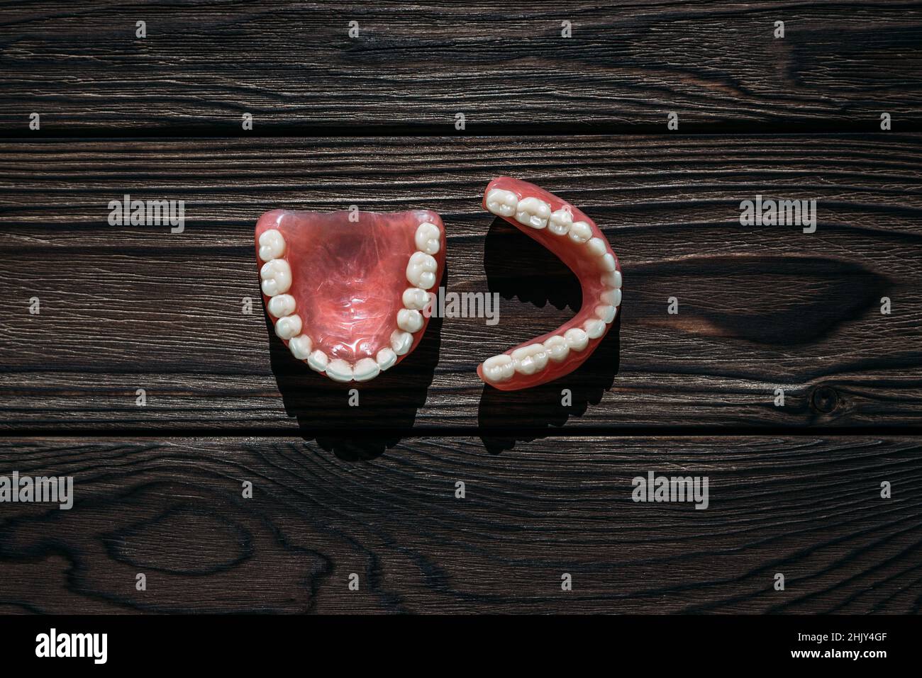 Dentiera completamente rimovibile in plastica delle ganasce. Una serie di dentini su sfondo scuro. Due protesi acriliche. Ganasce superiore e inferiore con denti falsi. Dentur Foto Stock