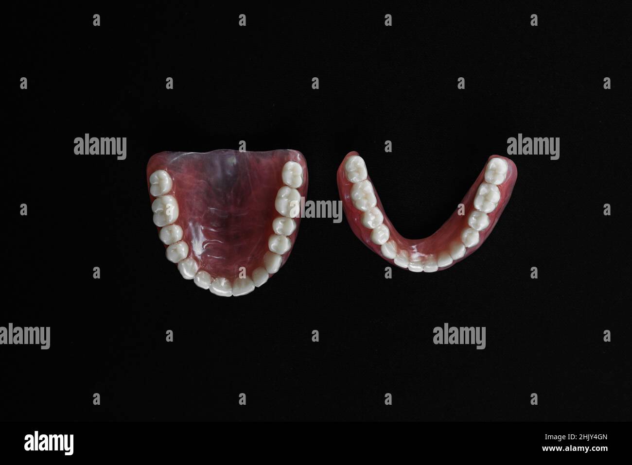 Dentiera completamente rimovibile in plastica delle ganasce. Una serie di dentini su sfondo nero. Due protesi acriliche. Ganasce superiore e inferiore con denti falsi. Dentu Foto Stock