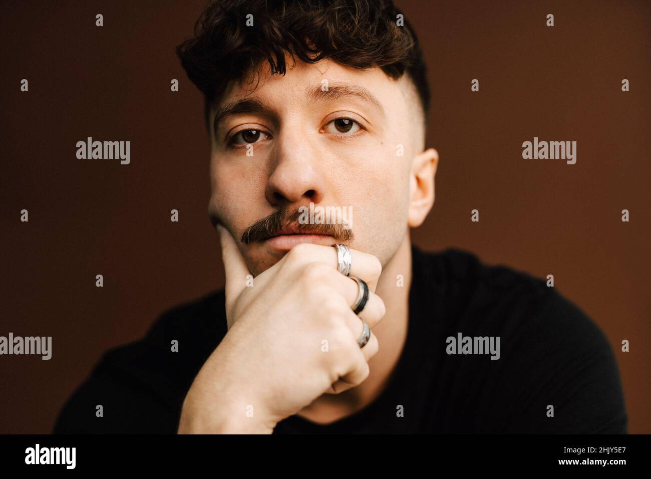 Ritratto del giovane uomo con mano sul mento in studio Foto Stock