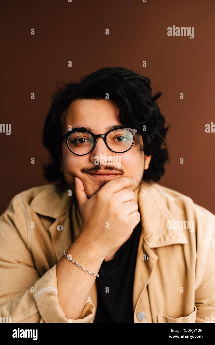 Ritratto di uomo con mano sul mento su sfondo marrone Foto Stock