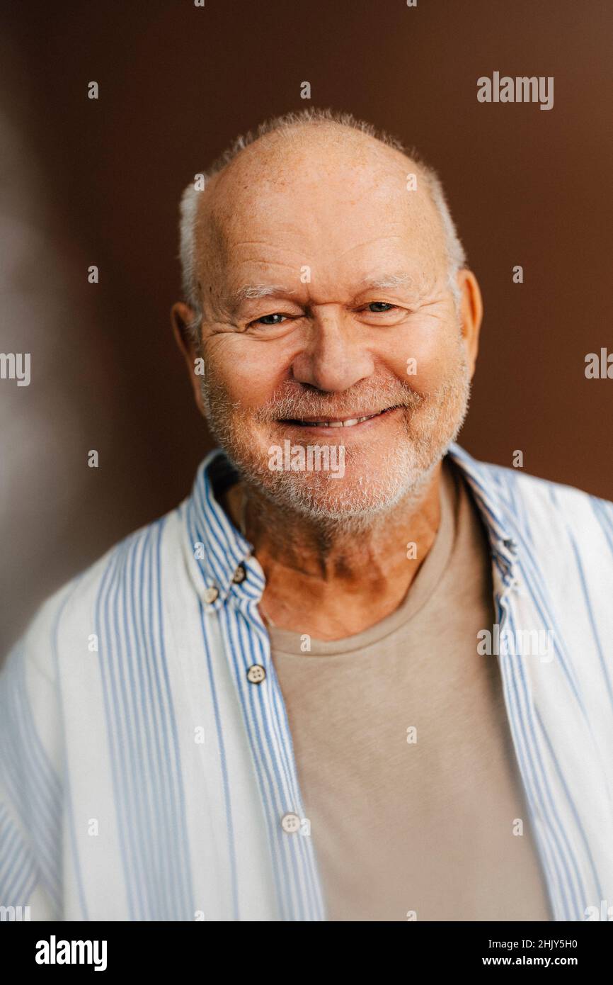 Ritratto di uomo anziano sorridente su sfondo marrone Foto Stock