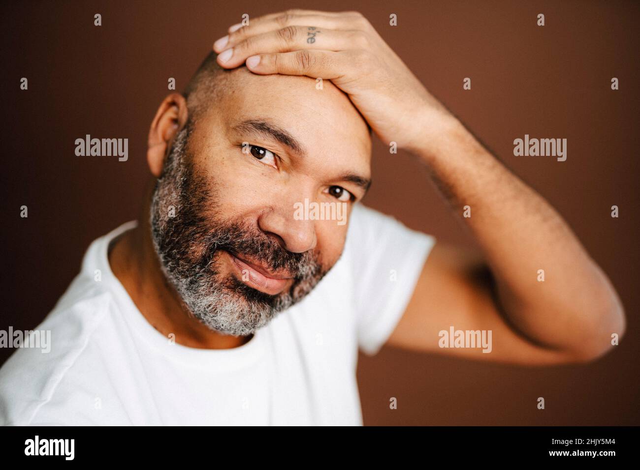 Uomo bearded che tocca la testa in studio Foto Stock