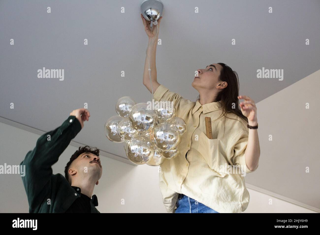 Donna lampadario appeso con ragazzo mentre si sposta in casa nuova Foto Stock