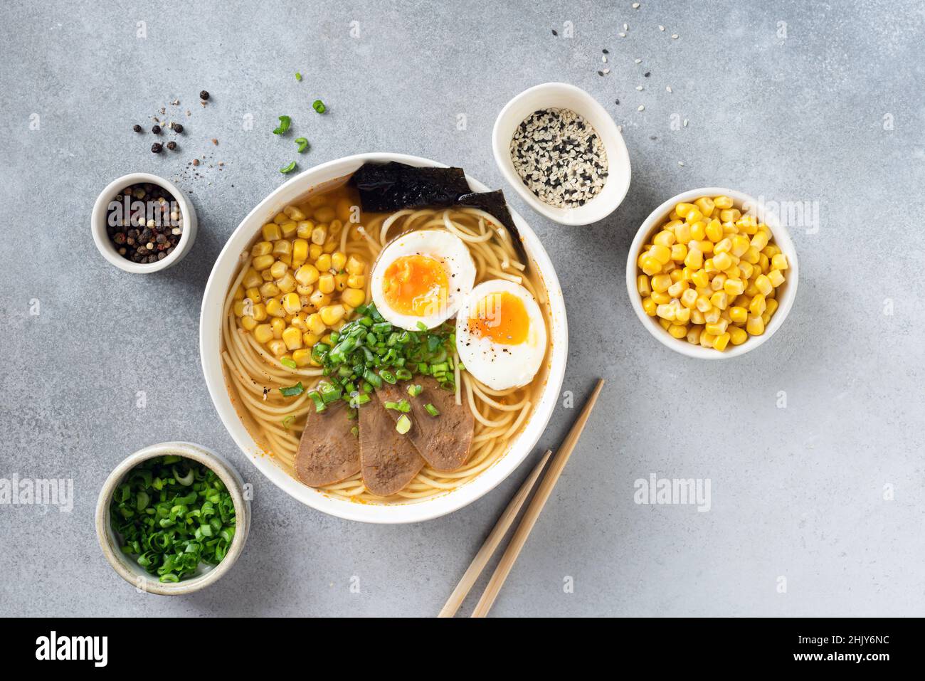 Ciotola ramen con uova e carne su sfondo grigio tavolo in cemento, vista dall'alto. Cucina asiatica Foto Stock
