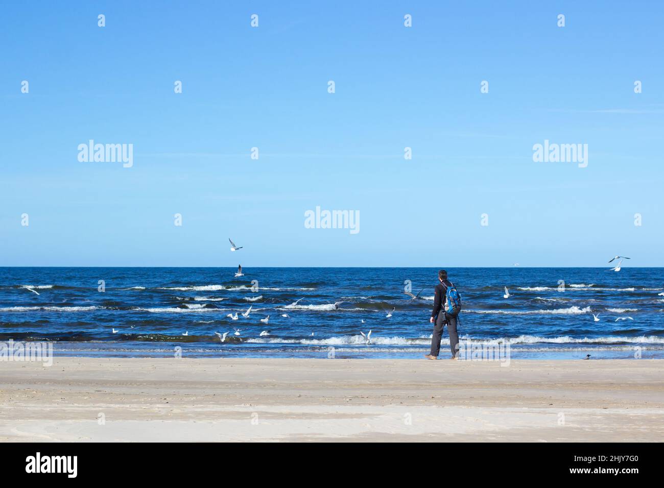 Blu Mar Baltico, l'uomo sta camminando sulla spiaggia. Jurmala Beach in Lettonia, vista autunnale Foto Stock