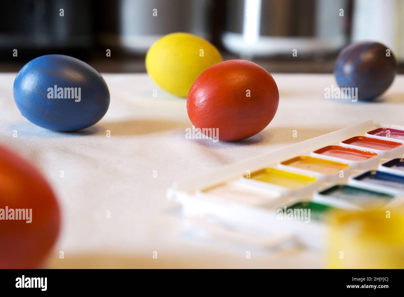 Uova di Pasqua colorate, pitture, un nido su un tavolo bianco nella sala da pranzo. Concetto di preparazione alla Pasqua. Scatto autentico. Vista laterale. Foto Stock