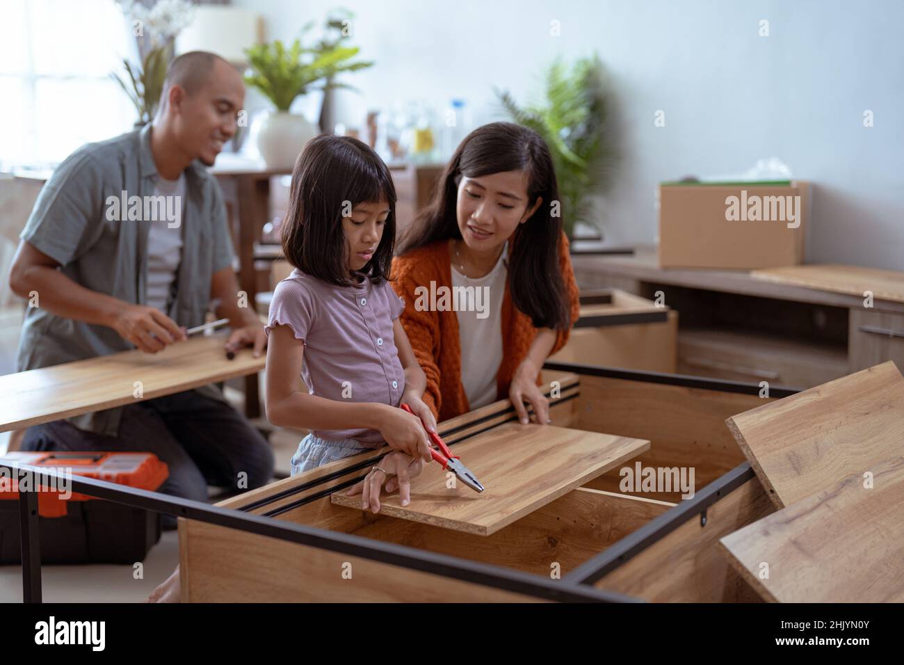famiglia asiatica alla loro nuova casa di acquisto e di assemblaggio di nuovi mobili. Foto Stock