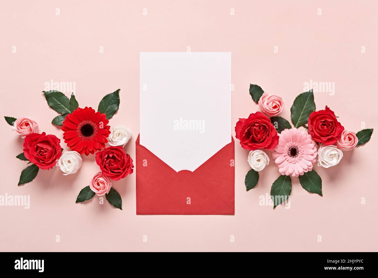 Busta rossa con mockup romantico lettera d'amore e fiori su sfondo rosa. Foto Stock
