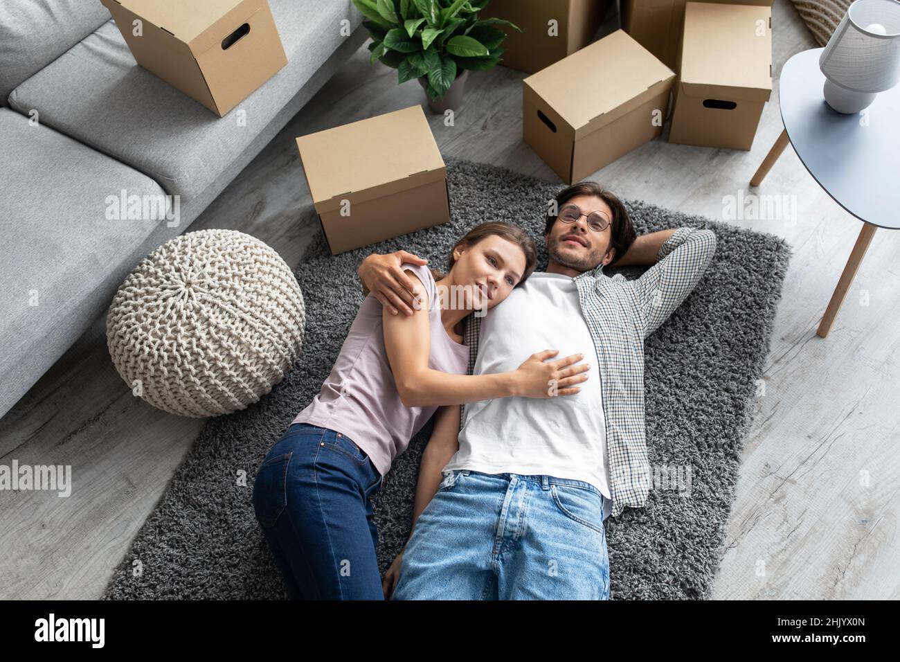 Stanco sorridente europeo marito e moglie si rallegra comprare nuovo proprio appartamento, si trova sul pavimento Foto Stock