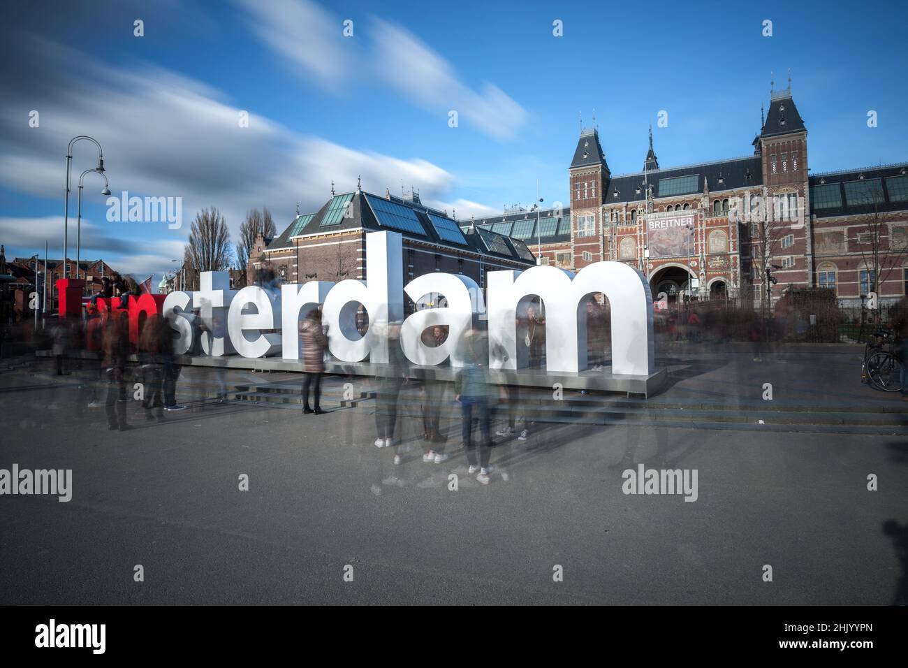 Enorme lettera 'i Amsterdam' di fronte al Rijksmuseum. Lunga esposizione con nuvole in movimento, cielo blu e turisti sfocati Amsterdam Olanda Foto Stock