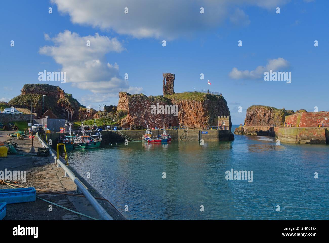 Affacciato a ovest sul porto di Dunbar, si trovano le antiche rovine storiche del castello. Bella giornata limpida. Barche colorate da pesca. Lothian orientale, Scozia, Regno Unito Foto Stock