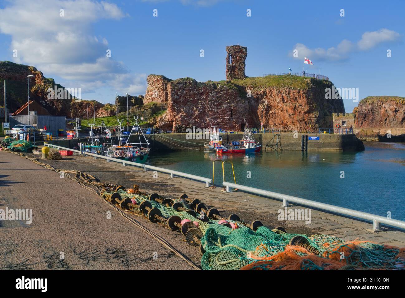 Affacciato a ovest sul porto di Dunbar, si trovano le antiche rovine storiche del castello. Bella giornata limpida. Barche colorate da pesca. Lothian orientale, Scozia, Regno Unito Foto Stock