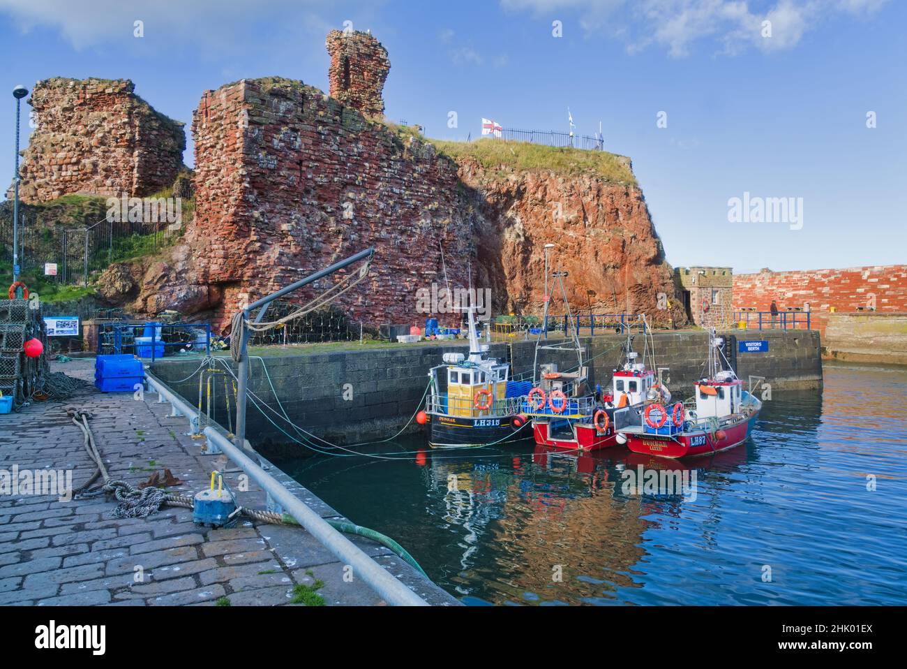 Affacciato a ovest sul porto di Dunbar, si trovano le antiche rovine storiche del castello. Bella giornata limpida. Barche colorate da pesca. Reti. Lothian orientale, Scozia, Regno Unito Foto Stock