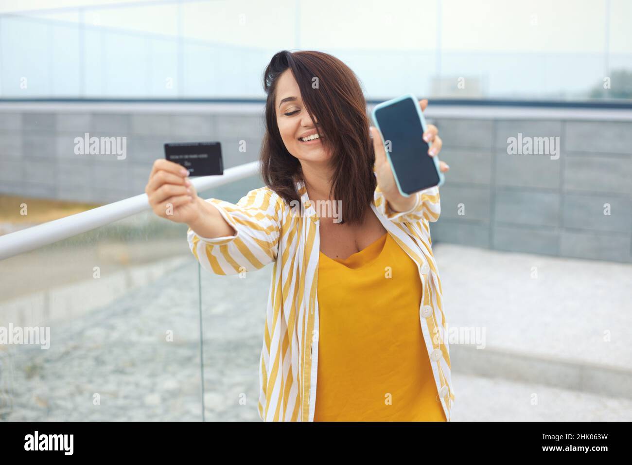 Lifestyle e ritratto urbano della donna emozionale di peso millenario possiede uno smartphone e una carta di credito bancaria Foto Stock
