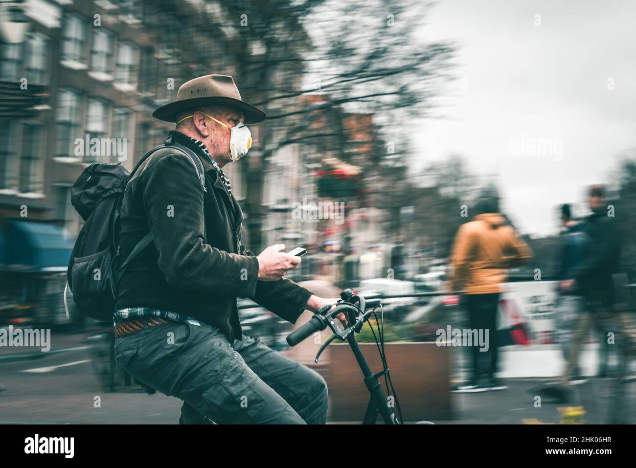 Bicicletta a cavallo con un telefono in una mano ad Amsterdam Paesi Bassi (Olanda) Europa Foto Stock