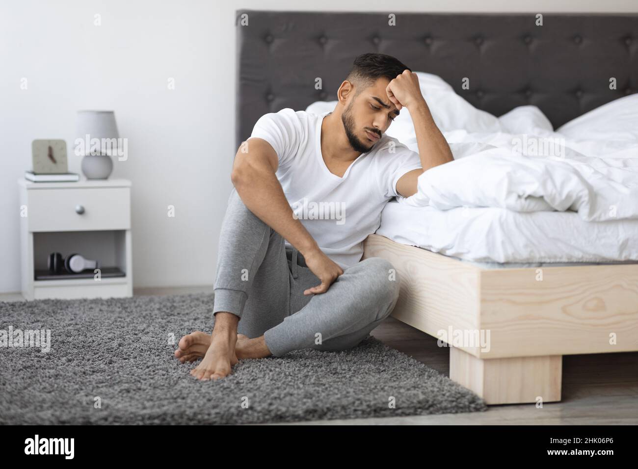 Concetto di malattia mentale. Depresso giovane ragazzo arabo seduto al piano vicino a letto Foto Stock