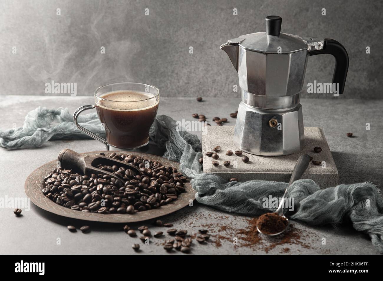Caffè caldo in una tazza di vetro e chicchi di caffè su sfondo chiaro. Foto Stock