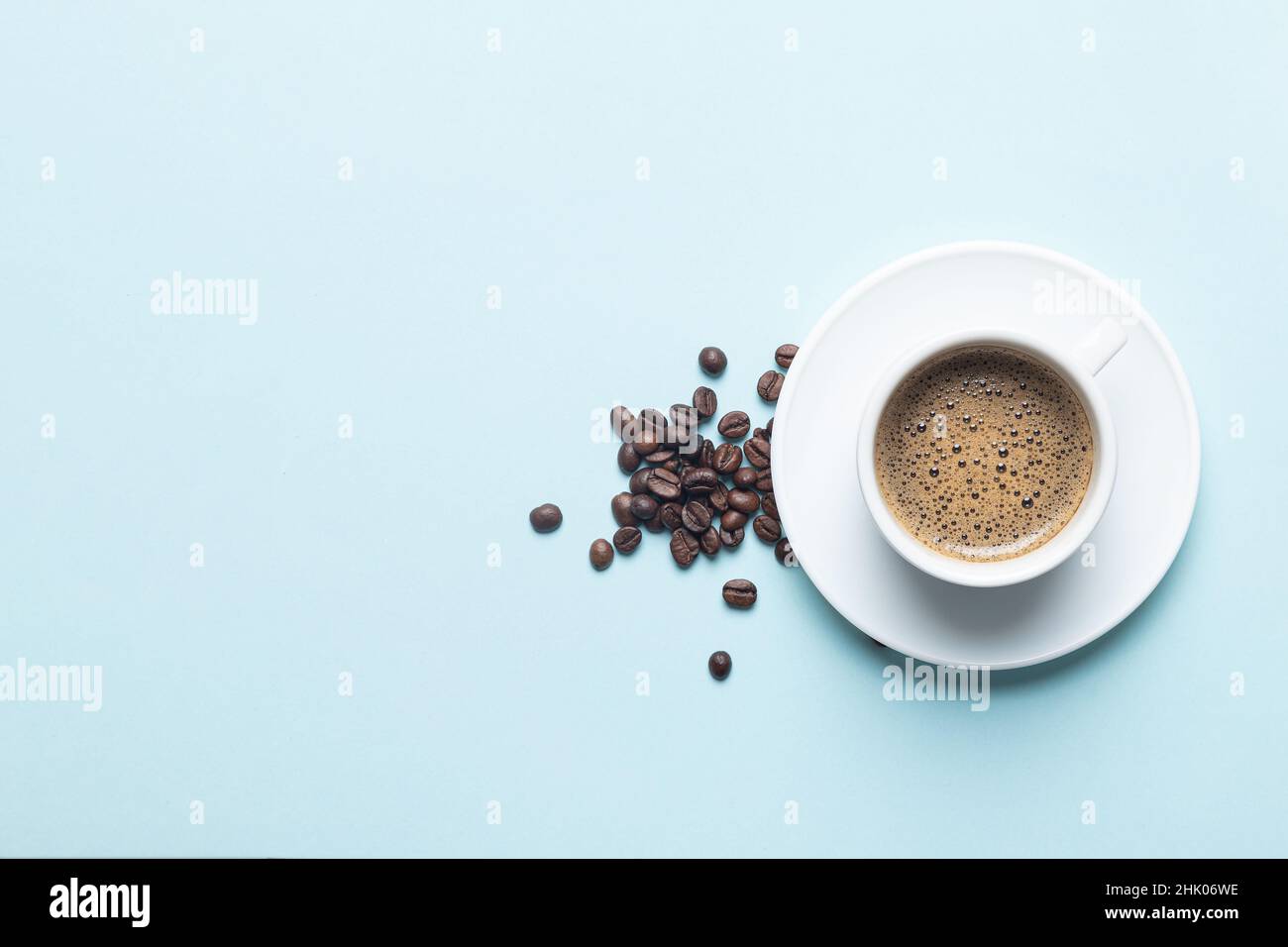 Tazza di caffè bianca con chicchi di caffè isolati su sfondo blu chiaro con spazio di copia. Foto Stock