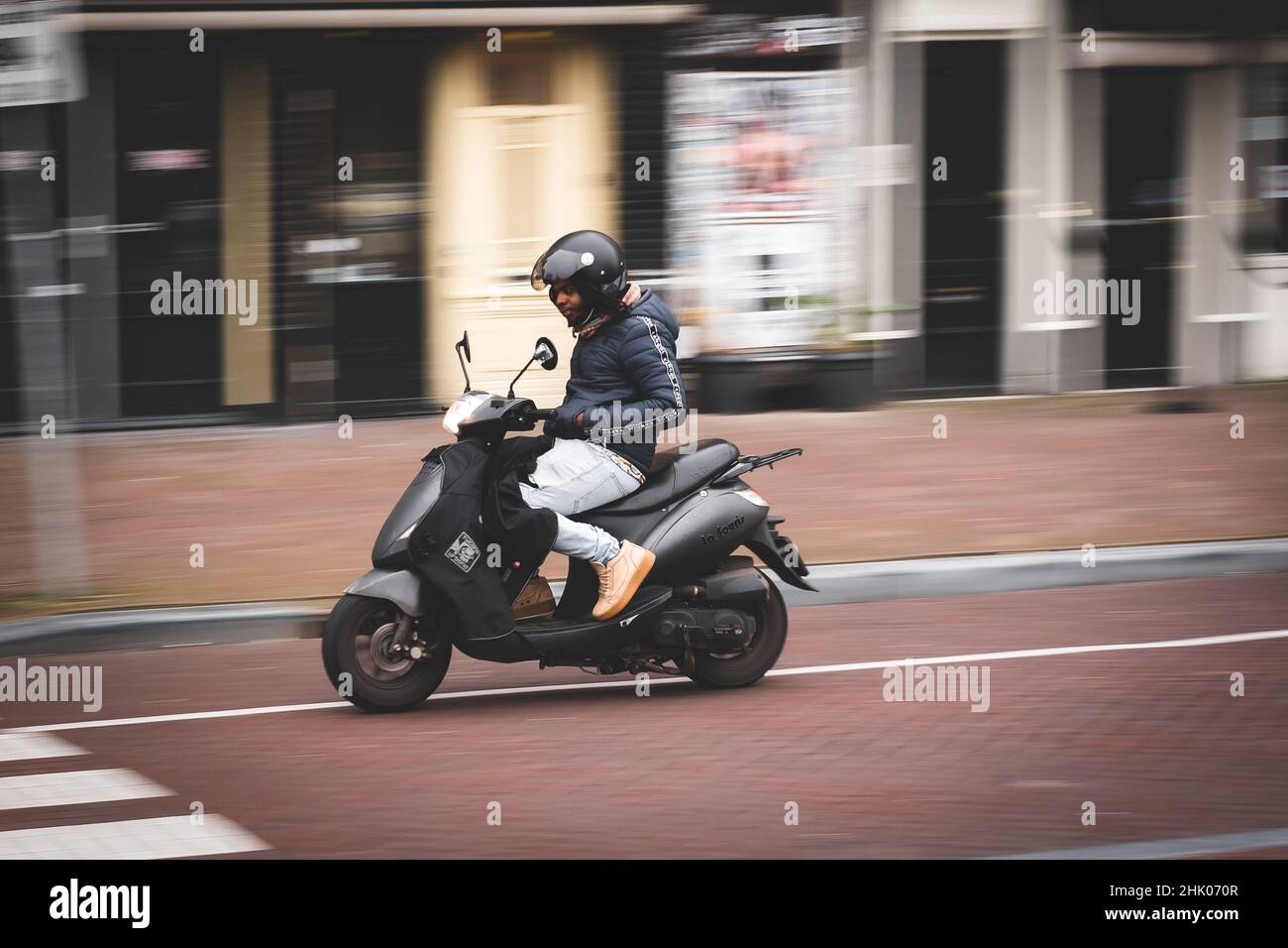 Guida di uno scooter senza mani al volante nella città di Amsterdam Foto Stock