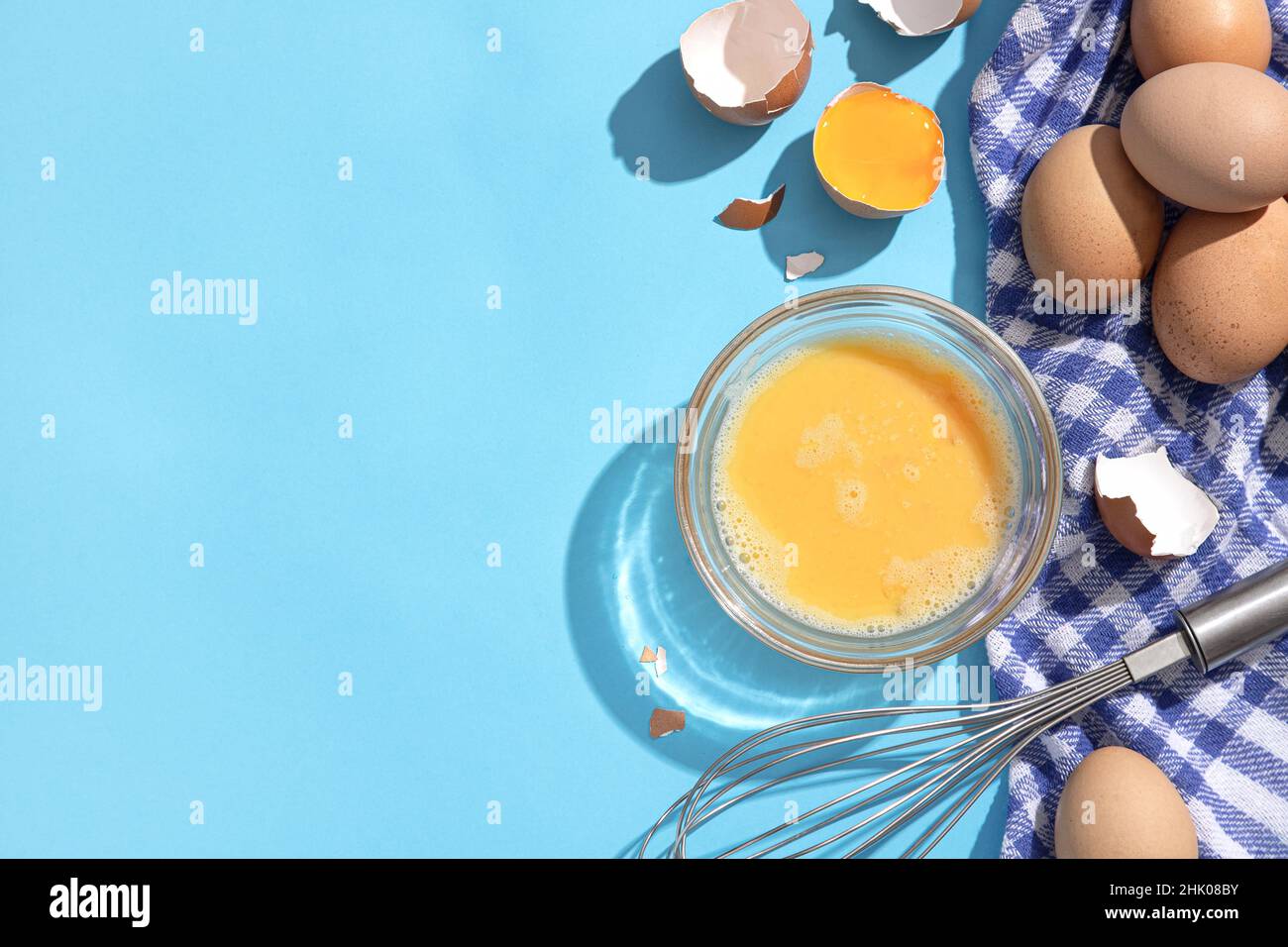 Uova sbattute su sfondo blu con copyspace. Disposizione piatta. Foto Stock