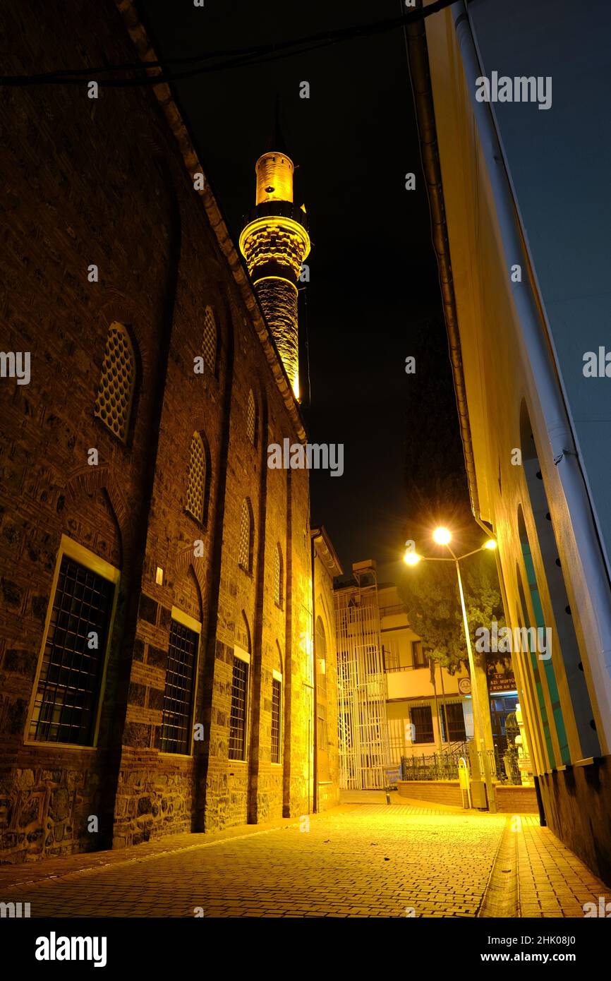 Foto notturna. Luci di strada strette e di strada con minareto moschea a Bursa. Foto Stock