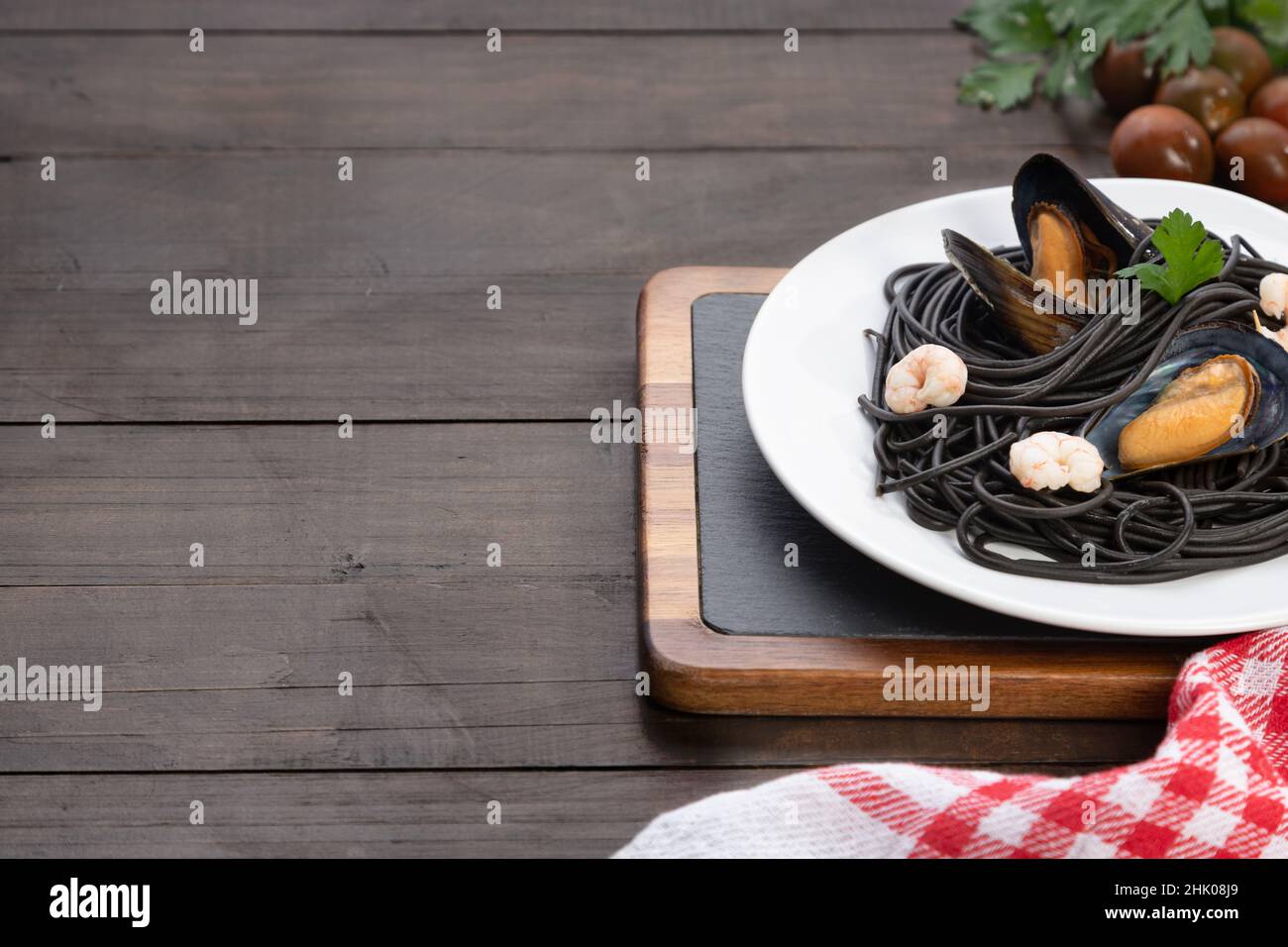 Piatto di pasta nera con frutti di mare su sfondo di legno con copyspace. Concetto di cucina mediterranea. Foto Stock