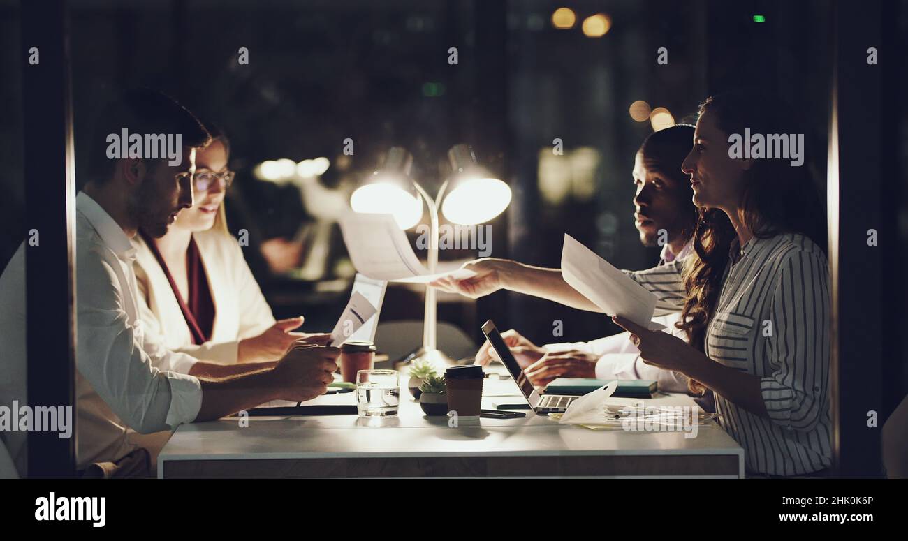 Dai un'occhiata a questi numeri. 4k filmati di un team di uomini d'affari che hanno una riunione a tarda notte nella sala riunioni. Foto Stock