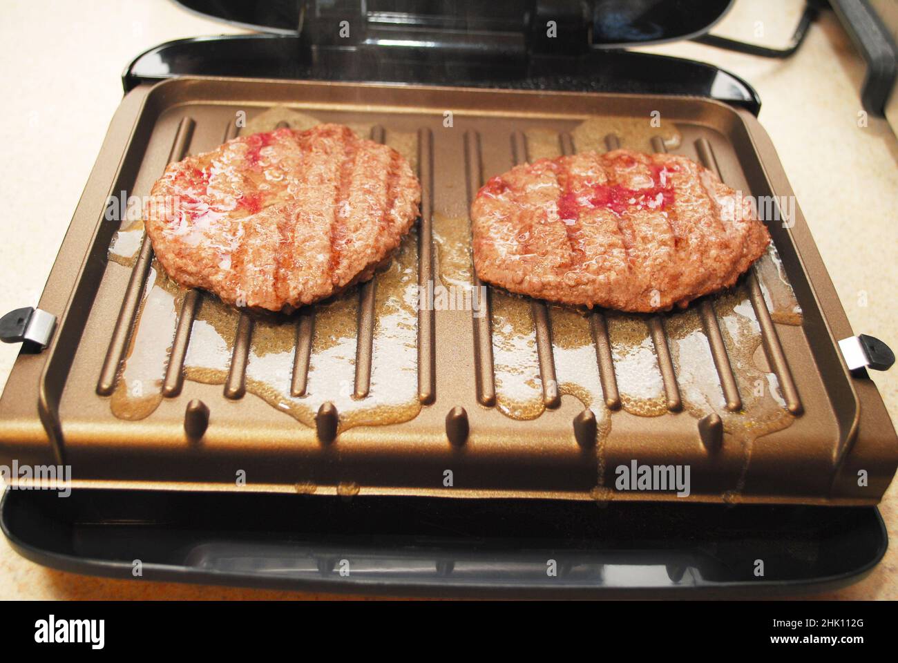 Due hamburger che cucinano su un grill al coperto Foto Stock