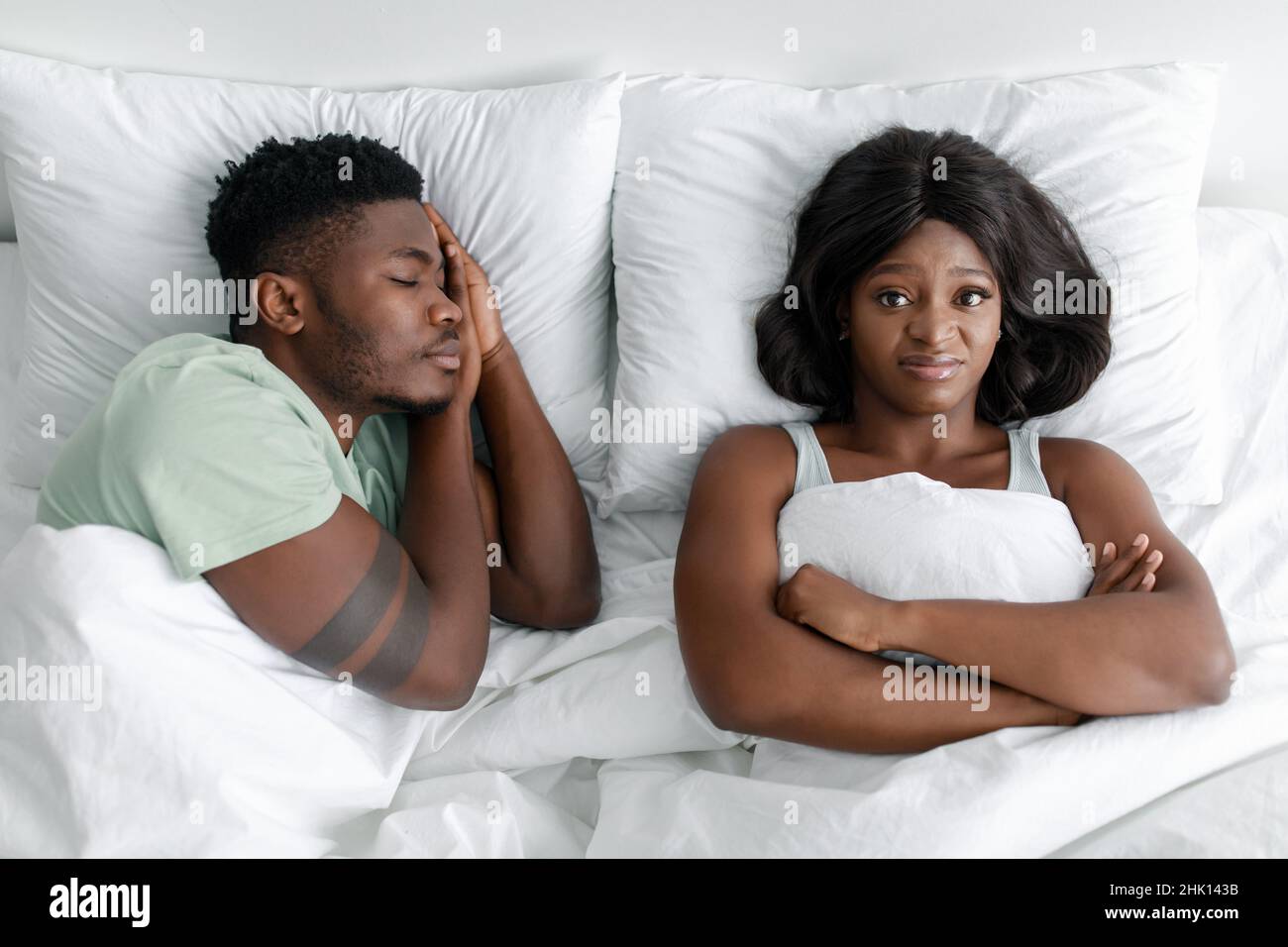 Dispiaciuti arrabbiato giovane ragazza afroamericana affetta da russare, uomo addormentato Foto Stock
