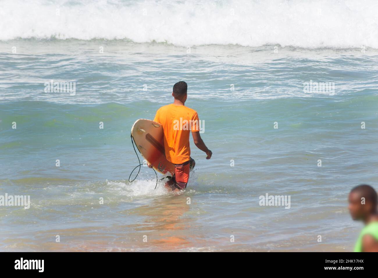 Surfista che entra in mare per fare surf alla spiaggia di Farol da barra nella città brasiliana di Salvador. Foto Stock