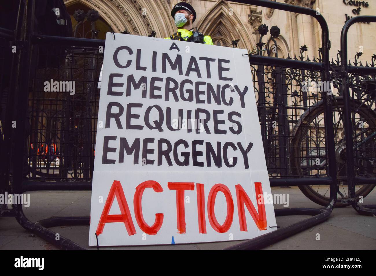 Londra, Regno Unito. 01st Feb 2022. Un ufficiale di polizia si trova accanto a un cartello "Climate Emergency" durante la protesta al di fuori delle corti reali di giustizia.19 insulate attivisti britannici sono in processo per la rottura dell'ingiunzione del M25. Quattro attivisti saltarono la loro audizione e si incollarono ai gradini all'ingresso dei tribunali. La Gran Bretagna, isolata, chiede al governo di garantire che tutte le case del Regno Unito siano più efficienti dal punto di vista energetico entro il 2030. Credit: SOPA Images Limited/Alamy Live News Foto Stock